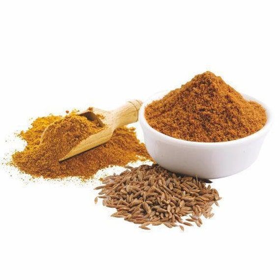 Spices including ground and whole spices with a wooden scoop on a white background